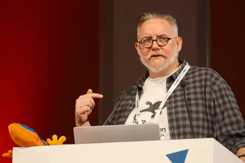 Martin wearing a lanyard and speaking at the podium at DrupalCon Barcelona 2024